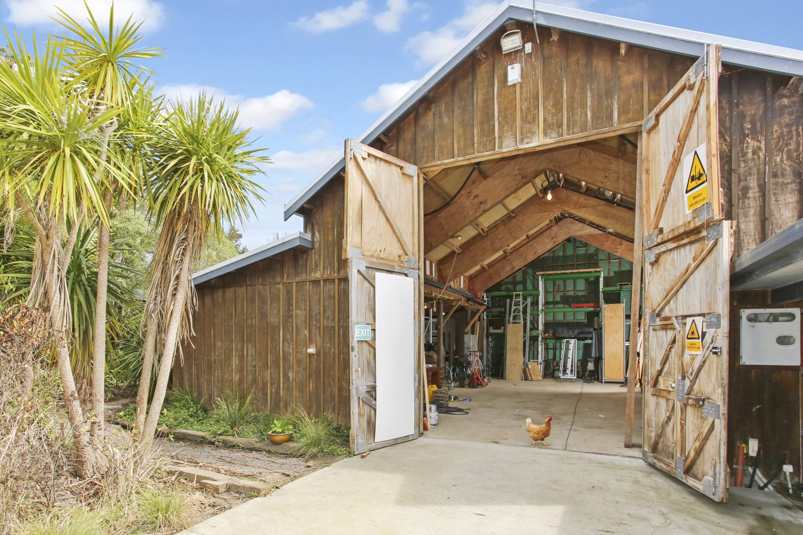 The barn warehouse with its gable end double doors open, showing the concrete floor and high stud inside